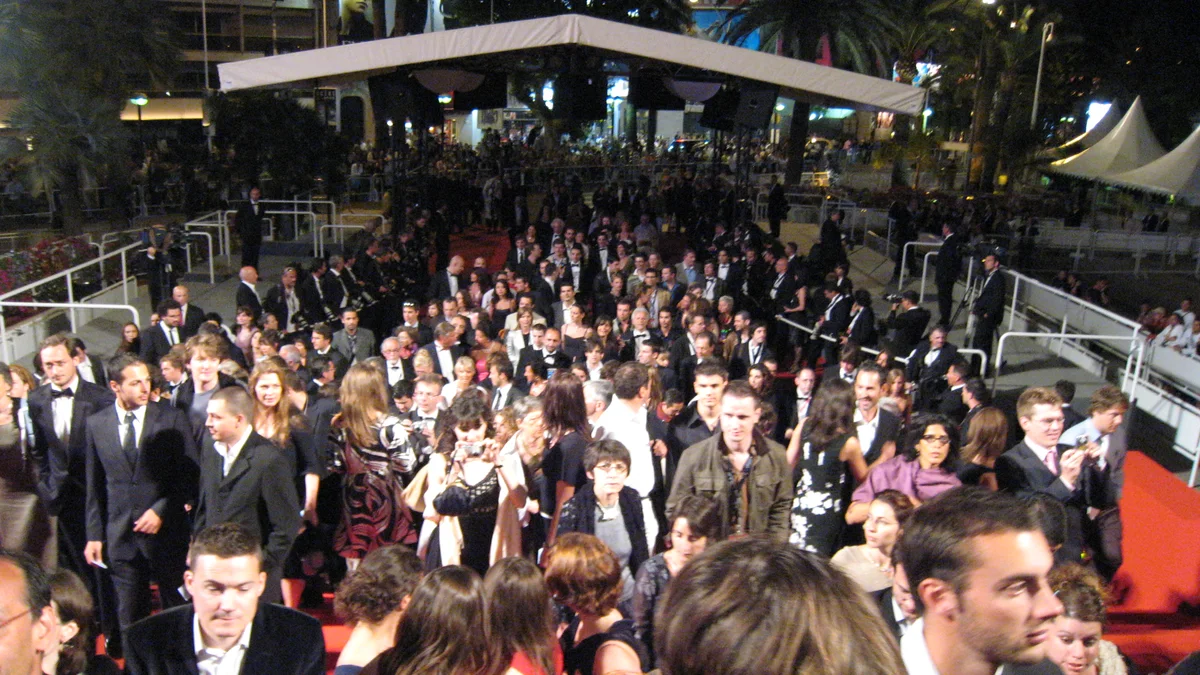 Guests in evening wear on the red carpet at the Cannes Film Festival, surrounded by photographers