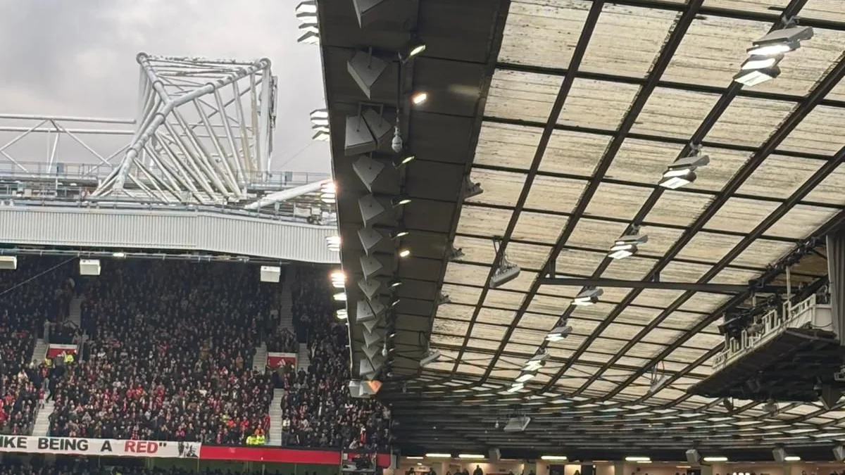 The packed stands of Old Trafford, with the stadium's distinctive roof structure, during a Premier League match