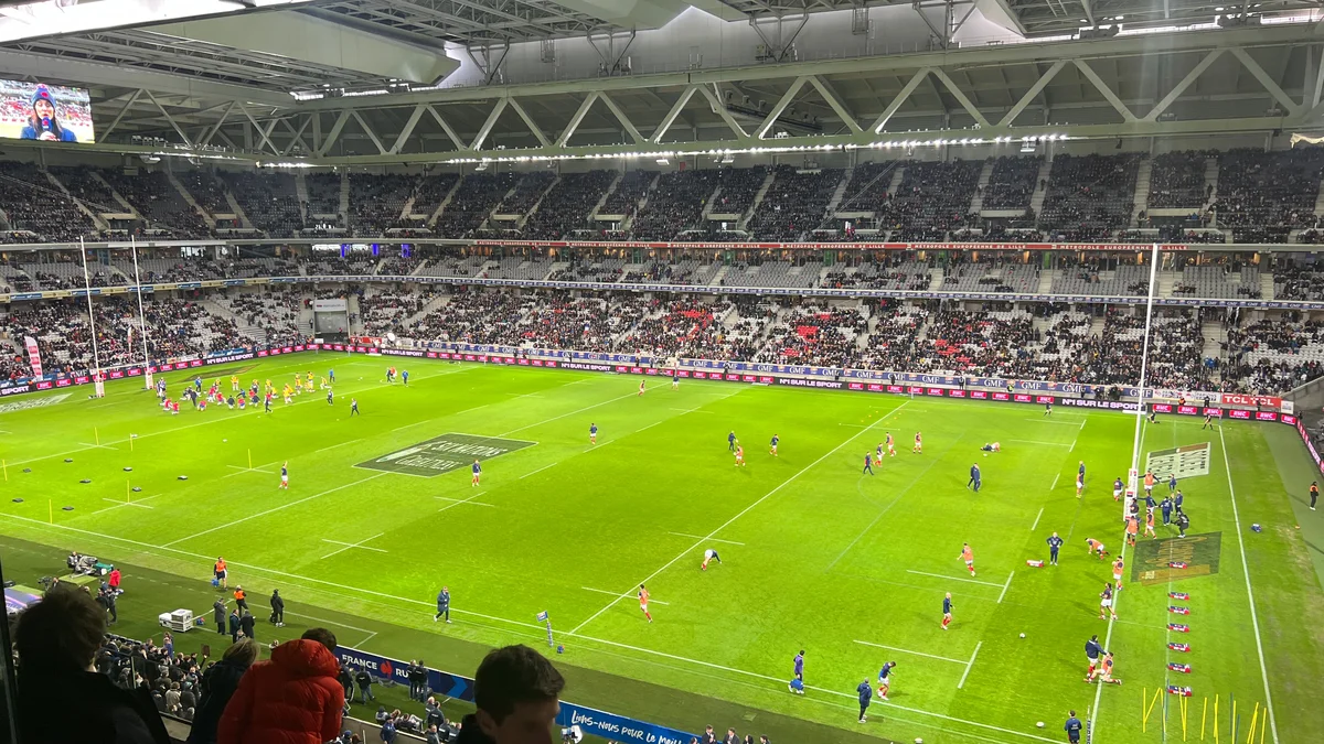 A packed rugby stadium under floodlights, players on the pitch, during a France XV match in the Six Nations Championship