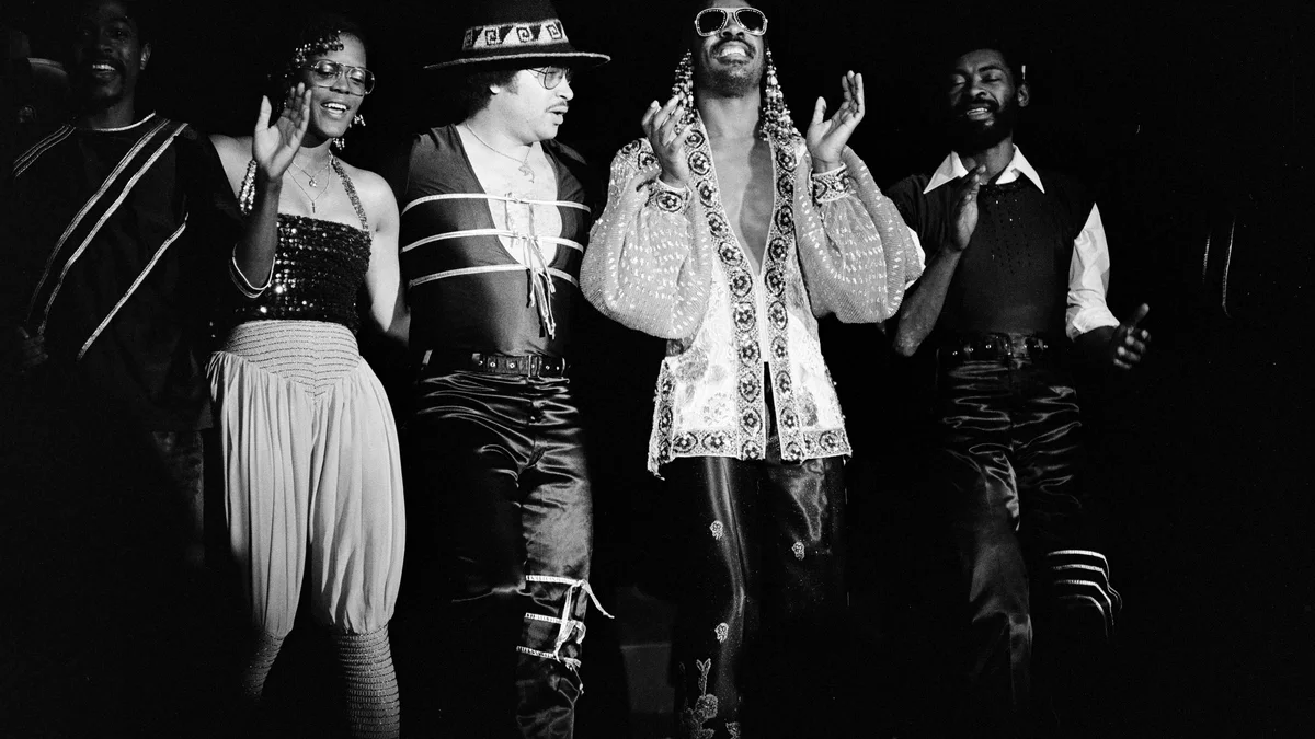 Stevie Wonder chante au micro sur scène avec ses musiciens, photo noir et blanc de 1981