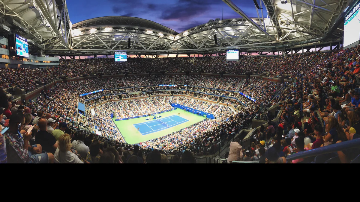 Vue panoramique de l'Arthur Ashe Stadium plein au crépuscule, toit ouvert, pendant un match de l'US Open
