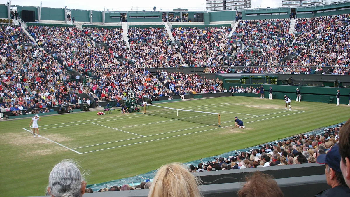 A packed Wimbledon Centre Court with the roof open, during a grass-court tennis match
